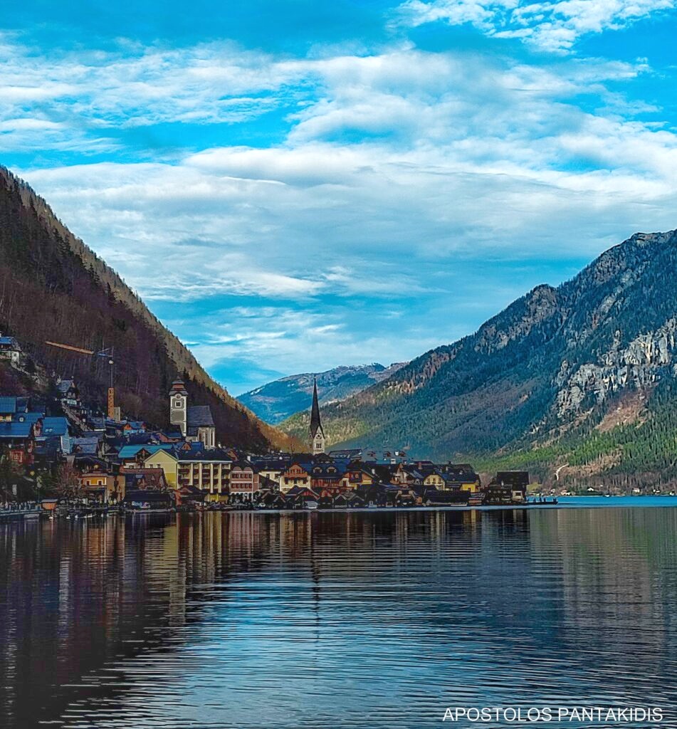 A breathtaking view of Hallstatt, where the charming alpine village meets the tranquil lake, creating a picture-perfect reflection. Surrounded by majestic mountains, this hidden gem of Austria feels like a scene from a fairy tale